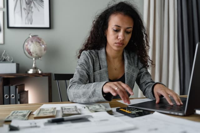 Woman sitting at a table and calculating the moving budget while looking stressed